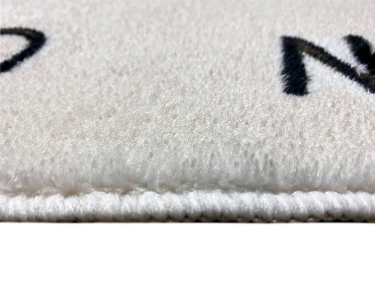 Kinderteppich-Detail: Flor und eingefasste Kante am Rand, mit schwarzer Schrift