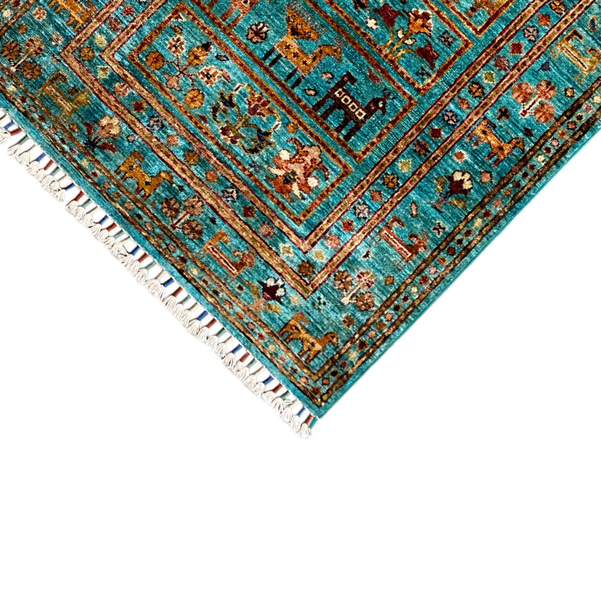 Close-up of the turquoise carpet corner with a border trim and white fringes, decorative field pattern.