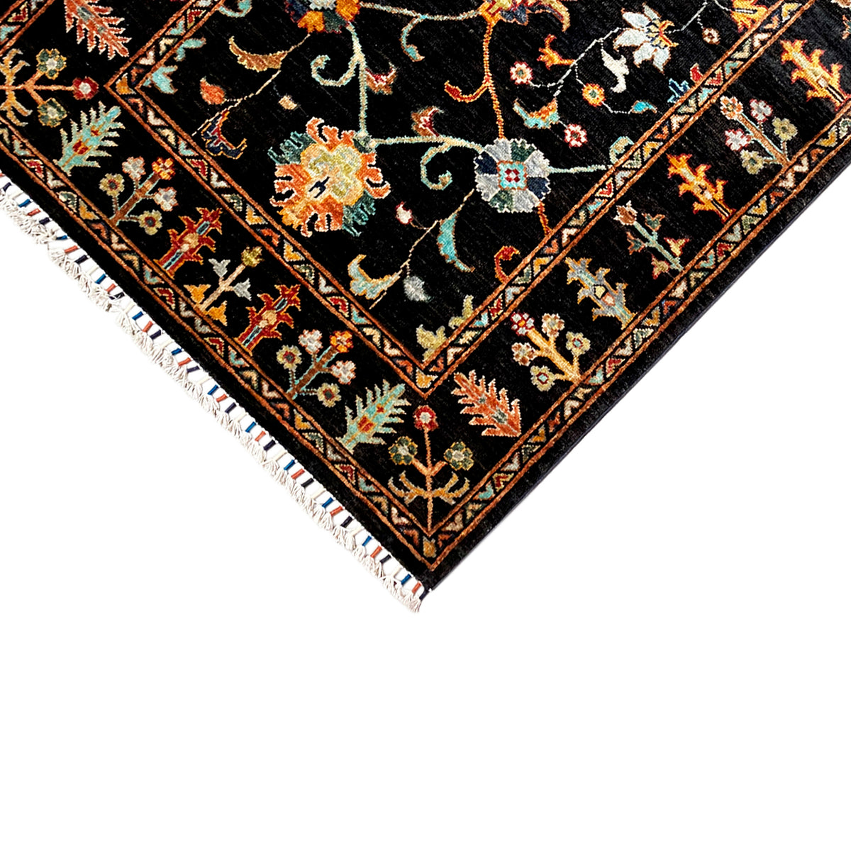 Corner of a Khorjin rug: dark pattern with colorful ornaments, white fringe along the edge