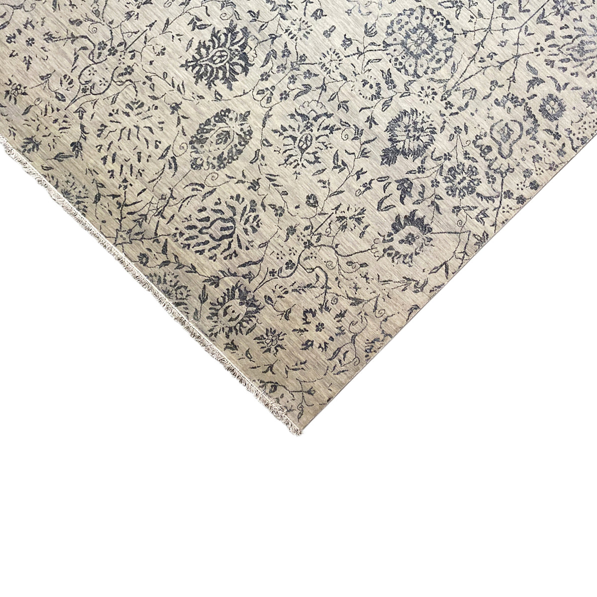 Corner detail with a frayed hem and blue ornamental pattern on a light background