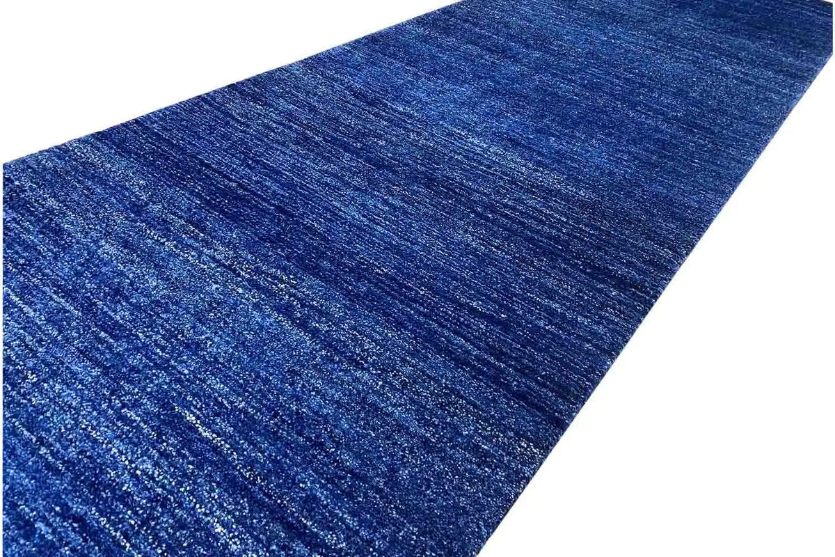 Close-up of a blue runner rug: mottled fibers, fine horizontal texture
