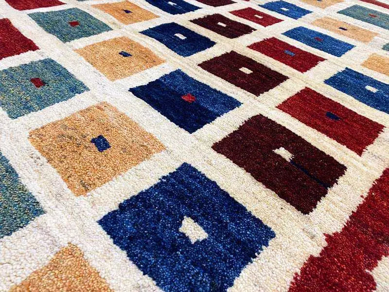 Gabbeh rug detail: tiled pattern with pile in blue, red, beige, and green