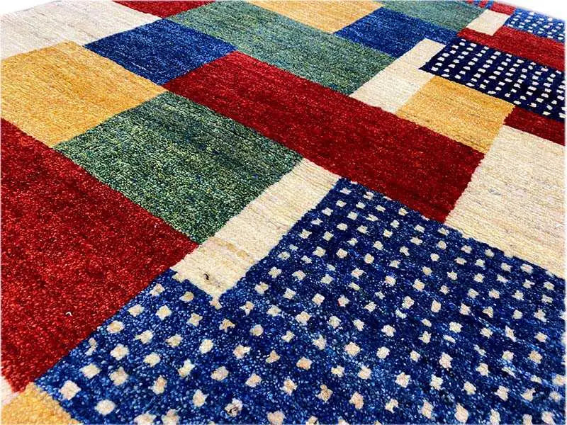 Close-up of a Gabbeh rug: block fields in red, green, blue, and beige with dots