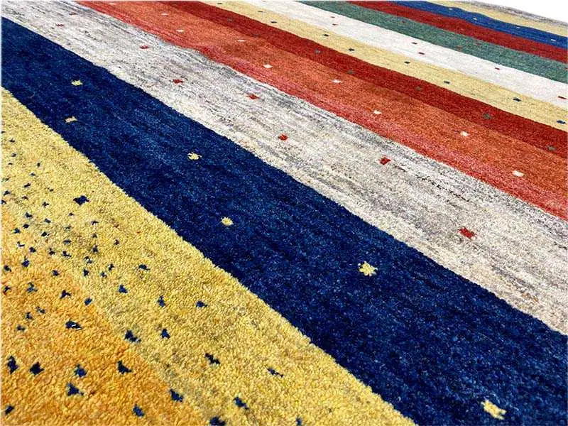 Gabbeh rug stripe detail with blue, red, and yellow bands as well as light areas