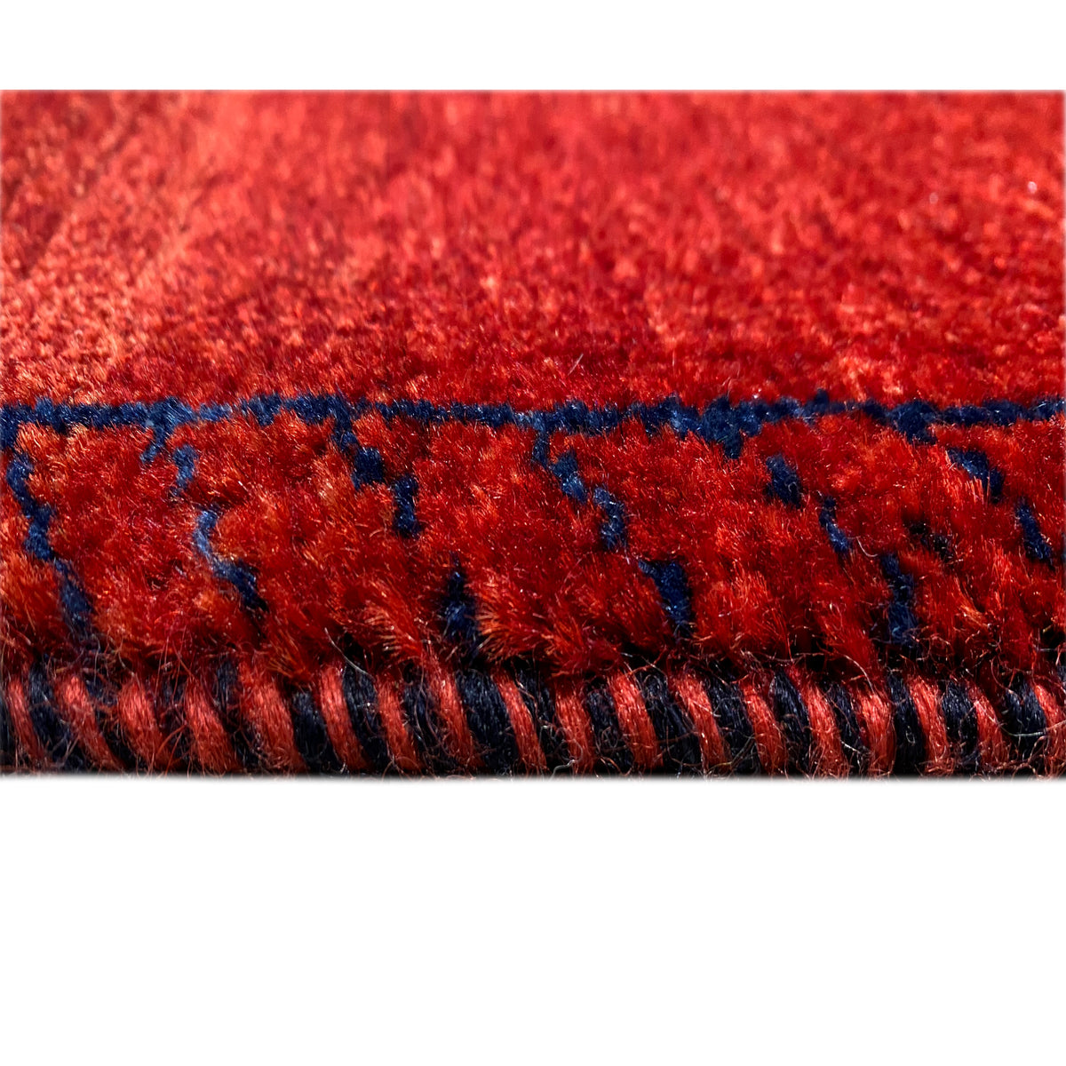 Edge view: red carpet with blue trim and short fringes along the edge