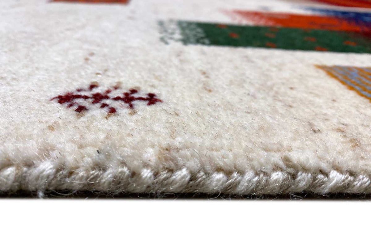 Close-up of a Gabbeh rug: dense, soft beige pile with a visible fiber texture
