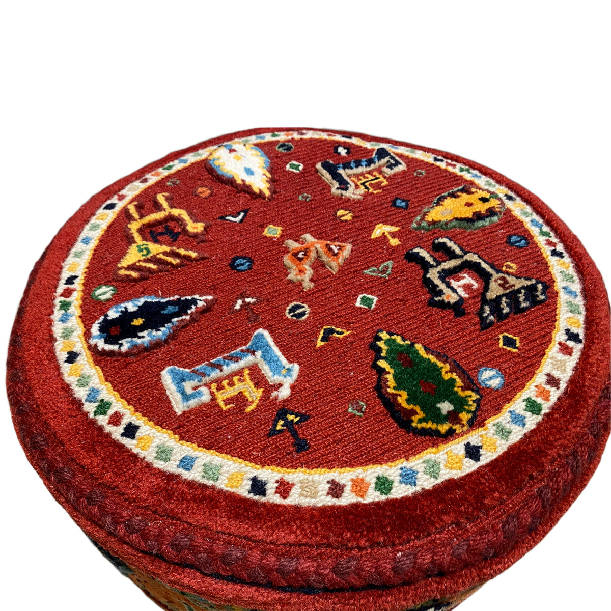 Close-up: red Soumak pattern on a round, padded stool seat with colorful motifs