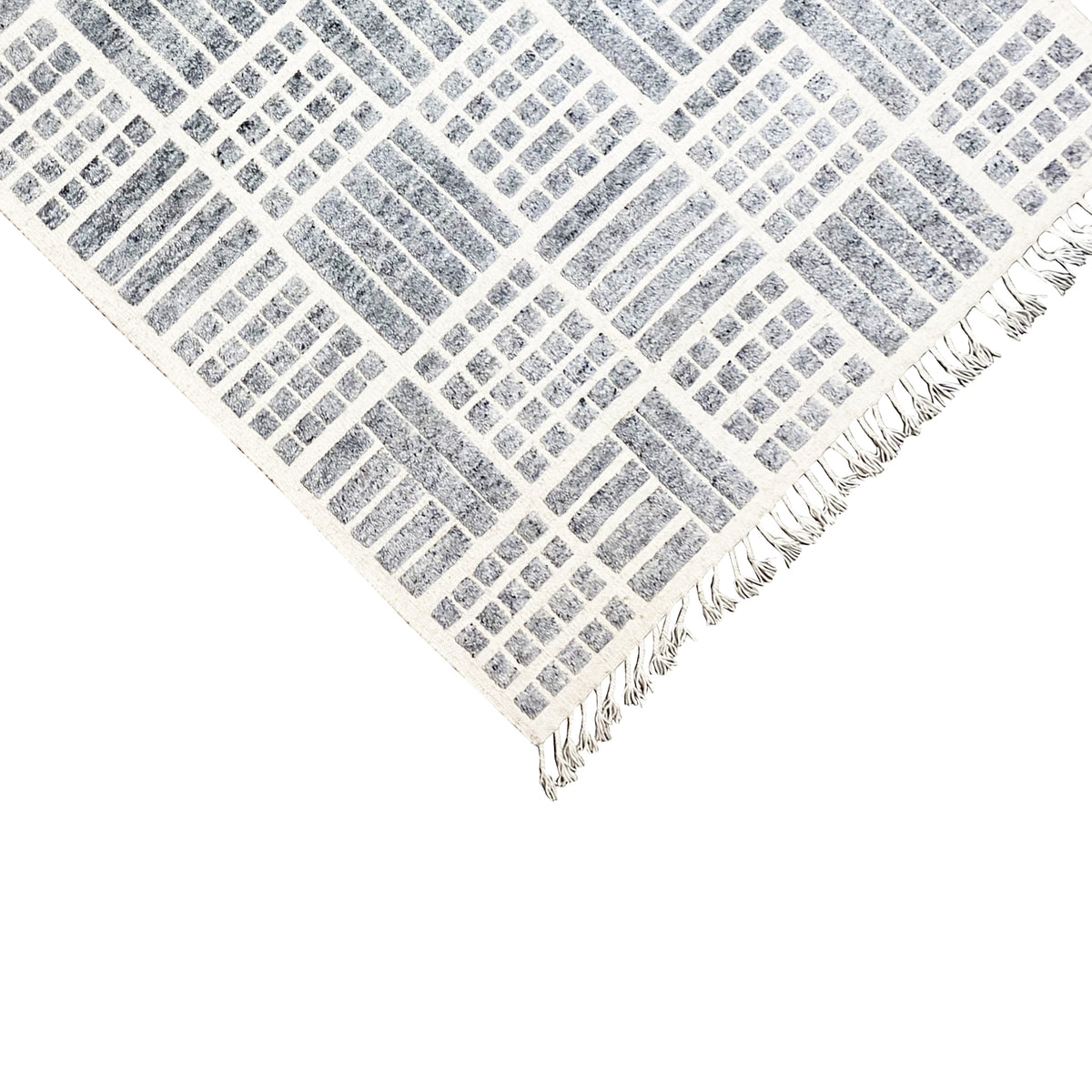 Corner view of a gray-and-white rug with a geometric grid and fringes