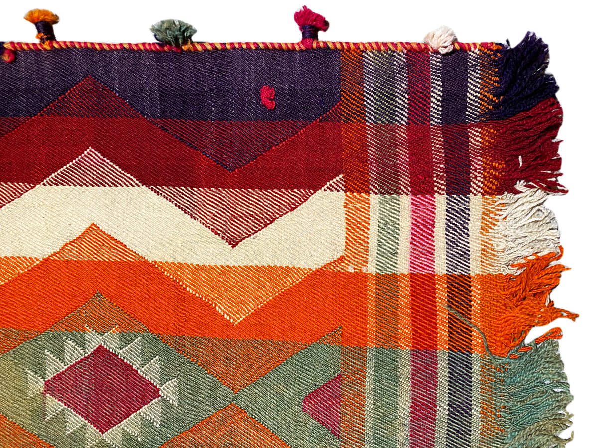 Detailed view of the Jajim rug: geometric diamonds and zigzags in orange, green, and blue