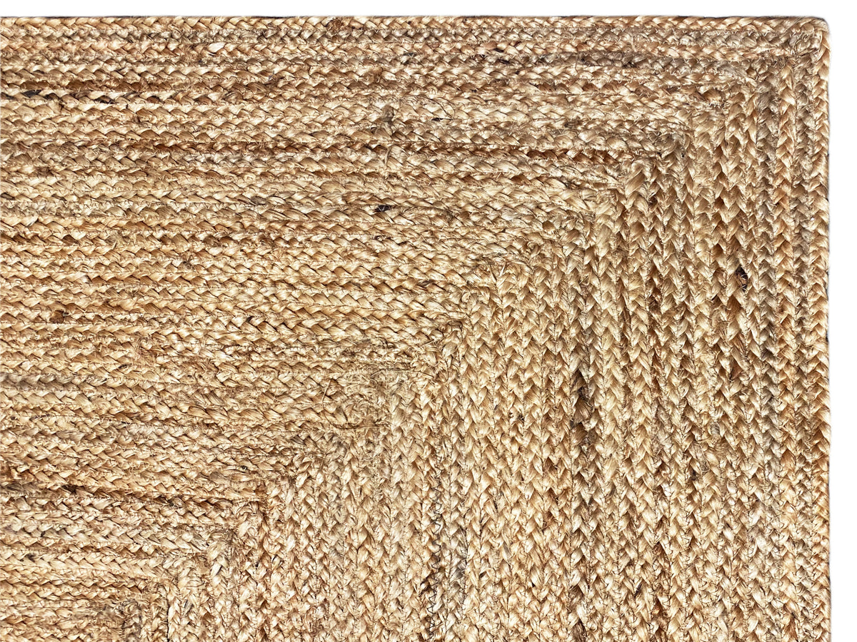 Close-up of a jute rug: dense beige weave with an embossed pattern and bordered edges