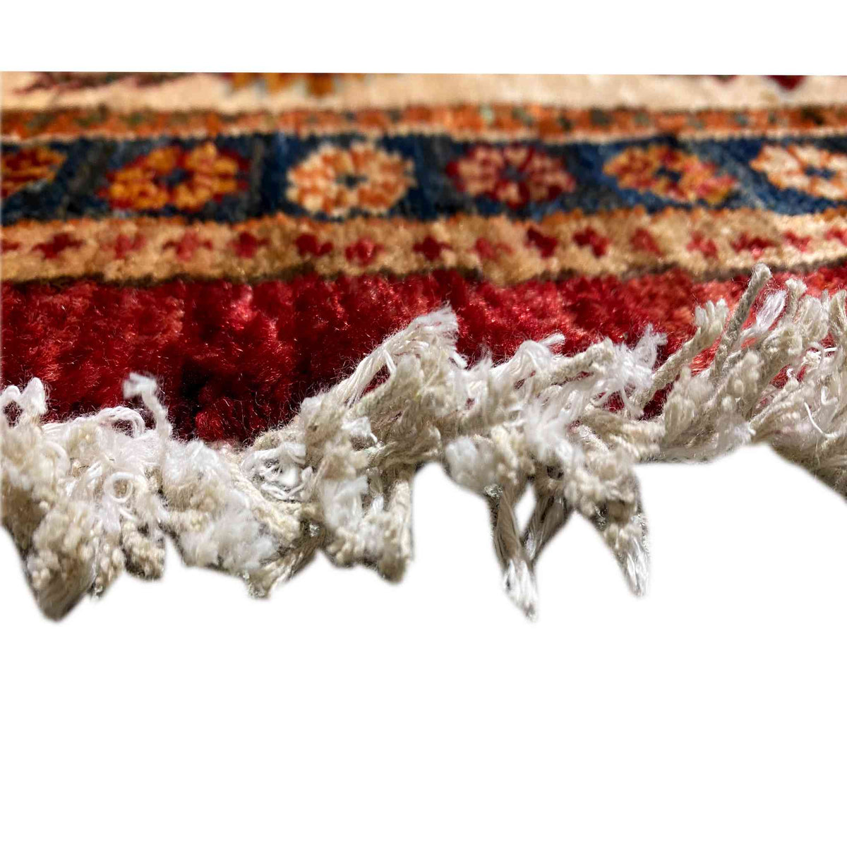 Close-up of the edge fringe on the round rug: reddish-brown pile, white trim