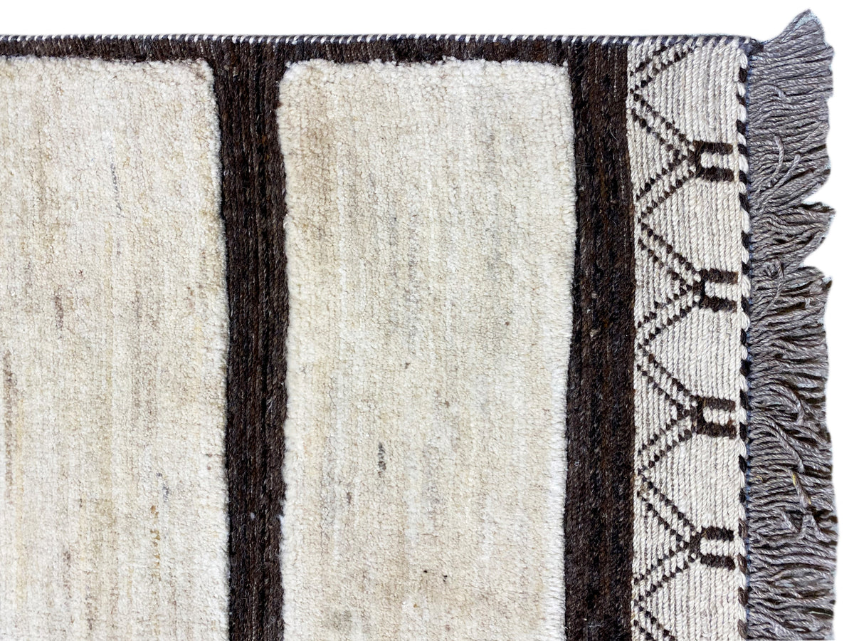 Close-up of the carpet edge: cream-colored stripes, dark trim, and fringe