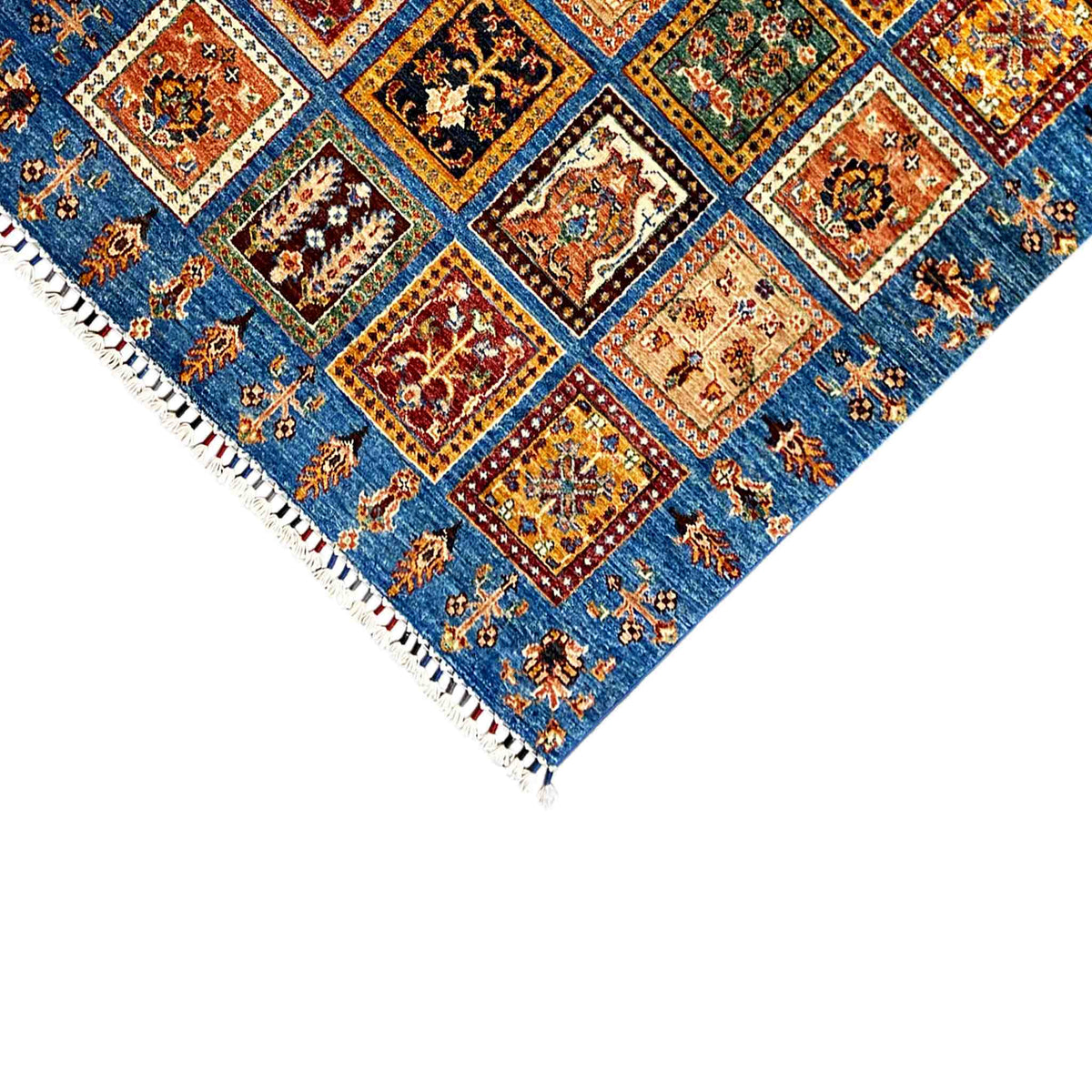 Carpet corner with a blue ornamental pattern and white fringes along the edge, close-up view