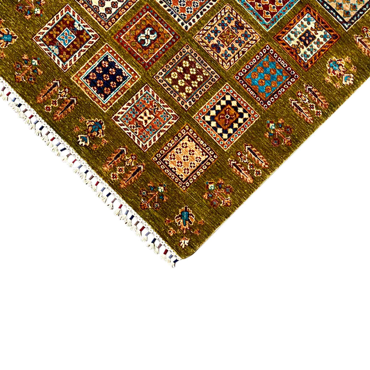Olive-green wool rug in the corner with a colorful pattern and white fringes