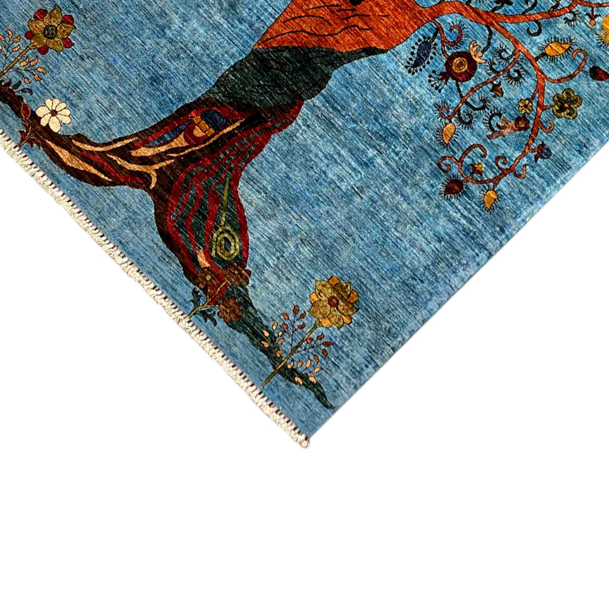 Corner with a figure and tree branches in orange/green on a blue rug, fringe