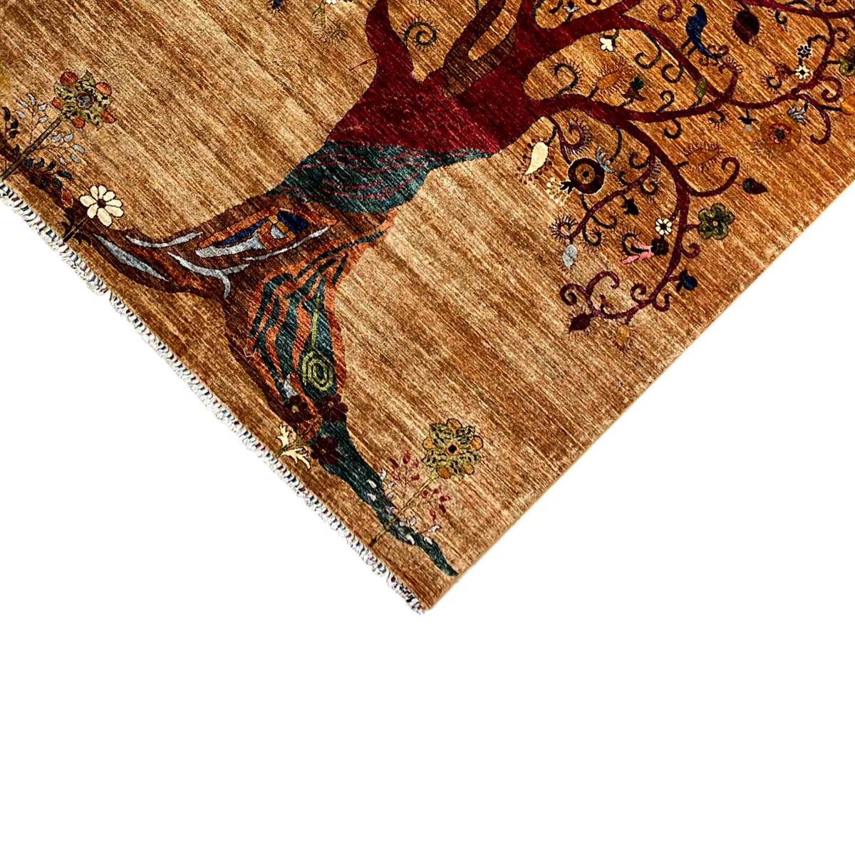Close-up of a corner: rug with a tree motif, colorful patterns, and fringes along the edge