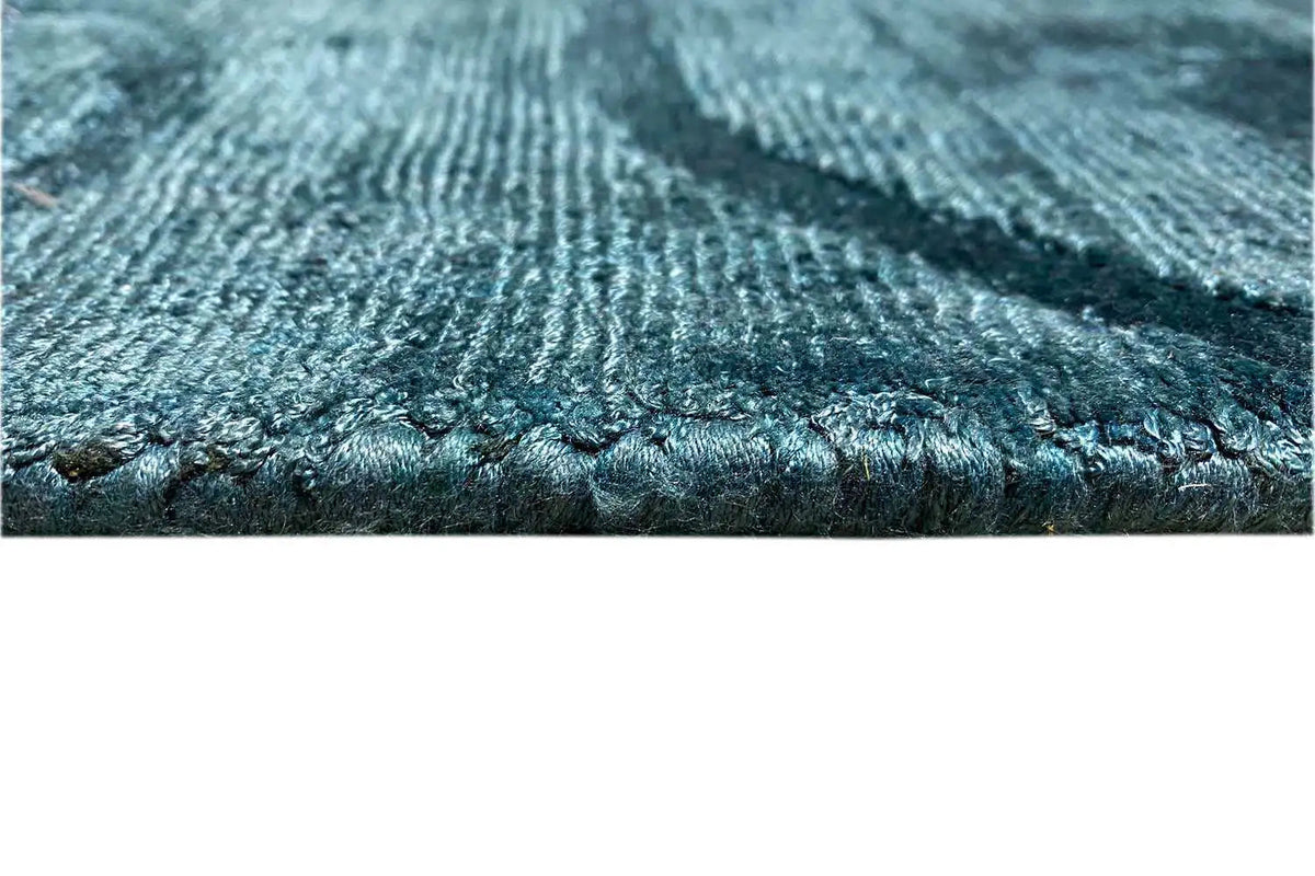 Close-up: blue carpet edge with a dense weave and short fringes