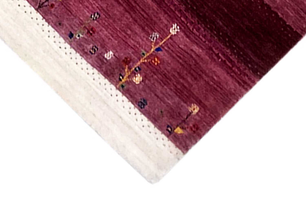 Gabbeh rug corner view: burgundy field, cream-colored border, small patterned lines
