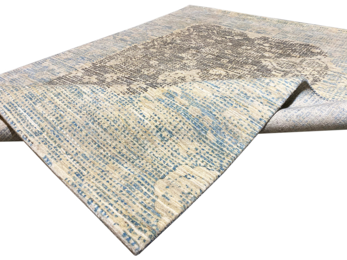 Blue-gray rug with a diagonal patterned area and a lightly hemmed edge