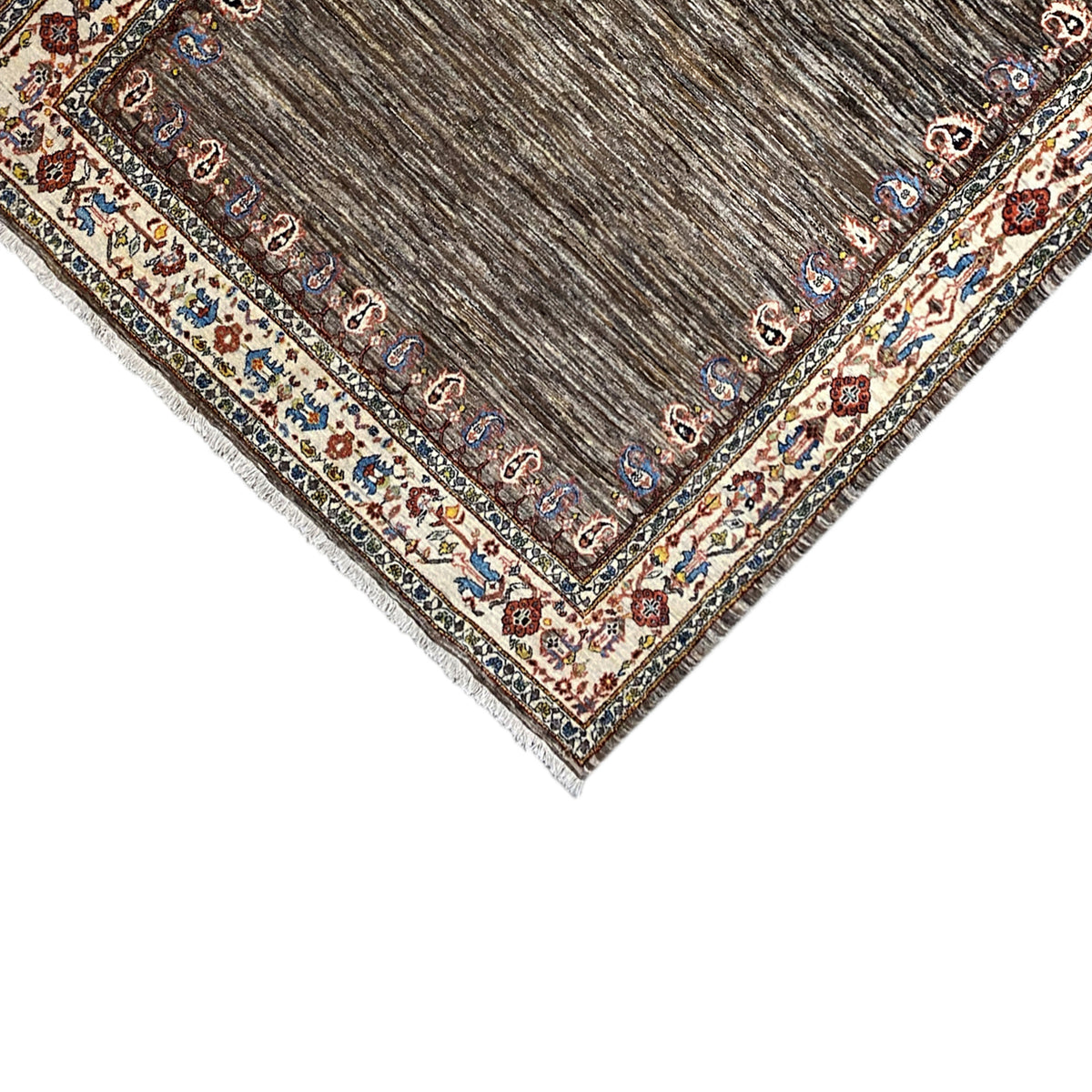 Corner of the rug: brown pile with a colored border and fringed edge