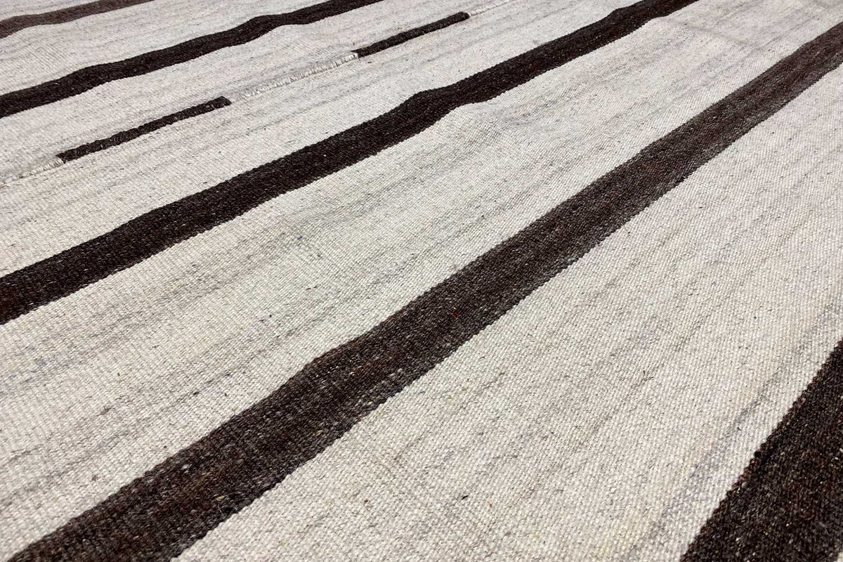 Kilim rug detail: woven texture with dark stripes and light spaces in between.