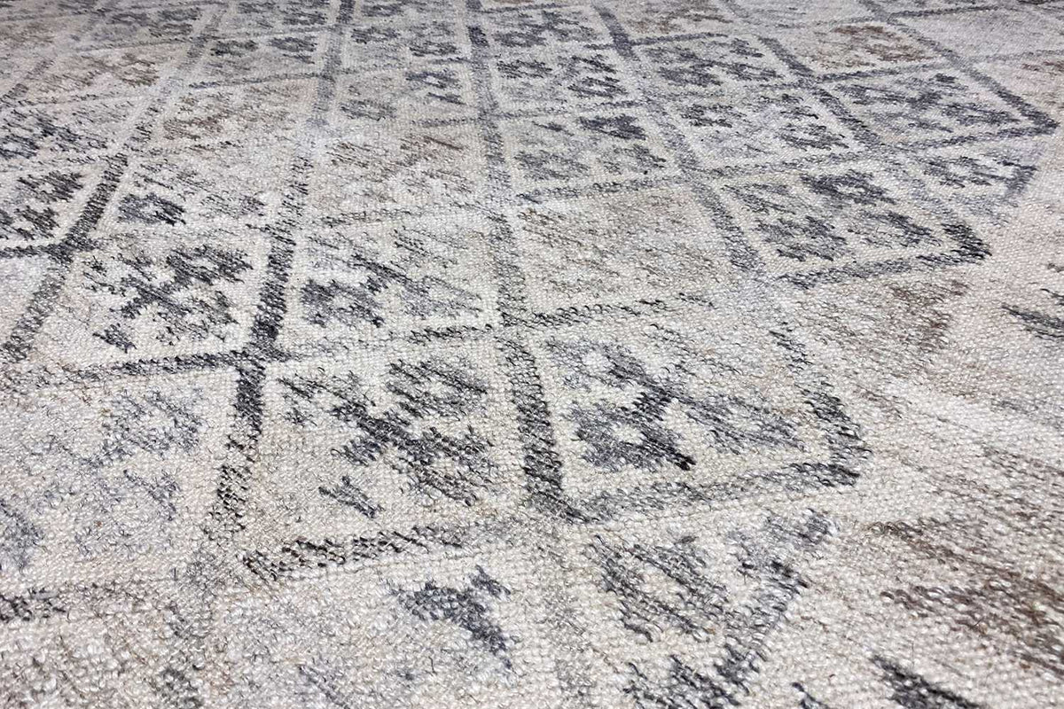Close-up of the kilim weave: light beige texture with blue-gray ornaments