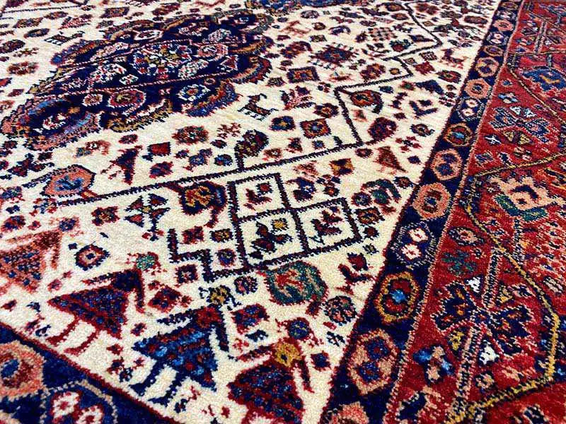 Close-up of the Qashqai carpet pattern: cream-colored field with blue-red ornaments