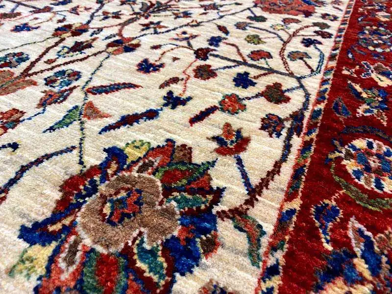 Detailed view: cream-colored carpet with blue-red floral ornaments and a red border