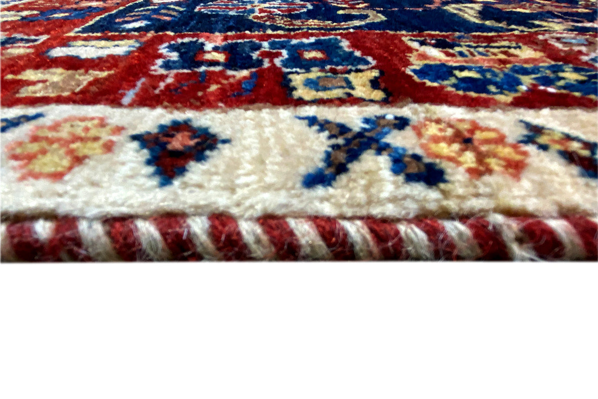 Close-up: carpet edge with fringe, multicolored pattern in red, blue, and beige