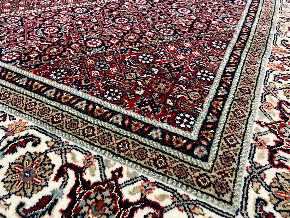 Bidjar carpet border detail: fine ornaments in dark red, cream, and blue with a border frieze