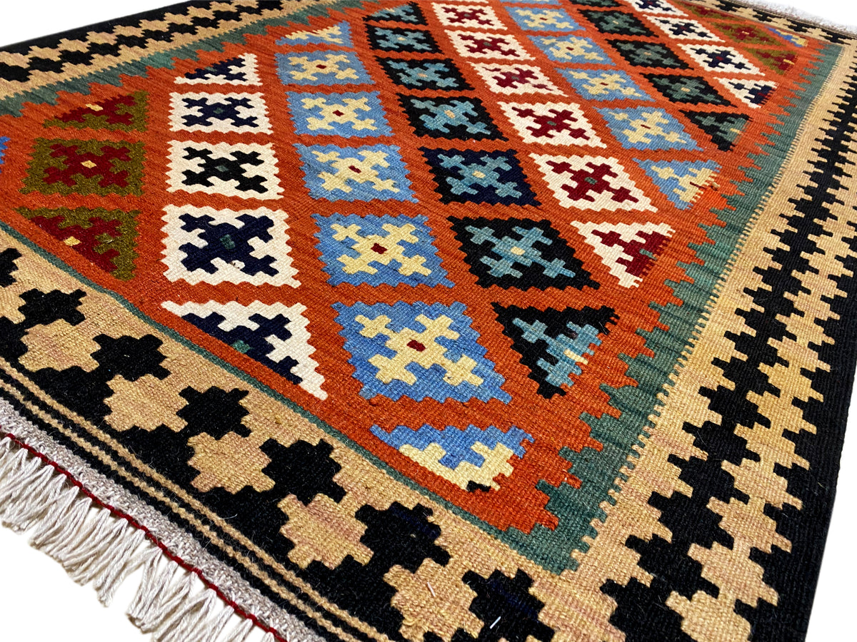 Close-up: kilim rug with colorful diamonds, cross motifs, and fringe along the bottom edge