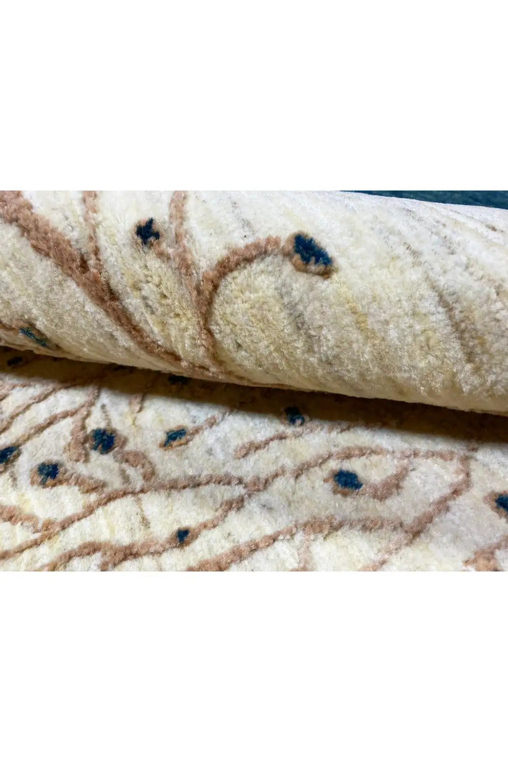 Close-up of a Gabbeh rug: textured surface with a cream background and blue dot accents.
