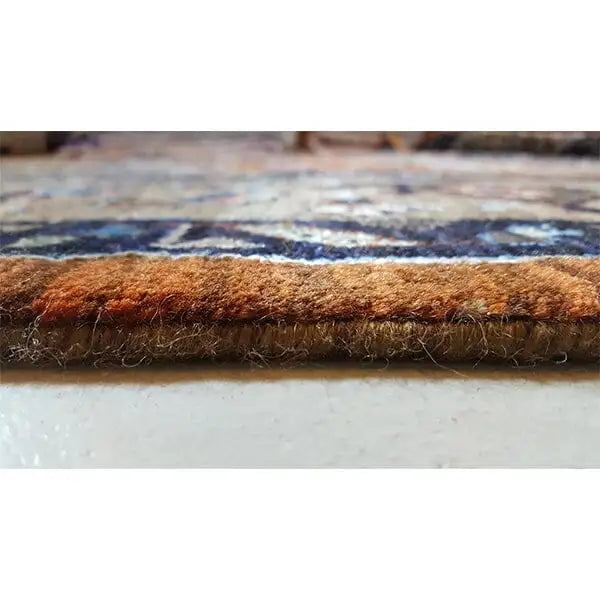 Designer rug: brown wool pile with a neatly finished rug edge in detail