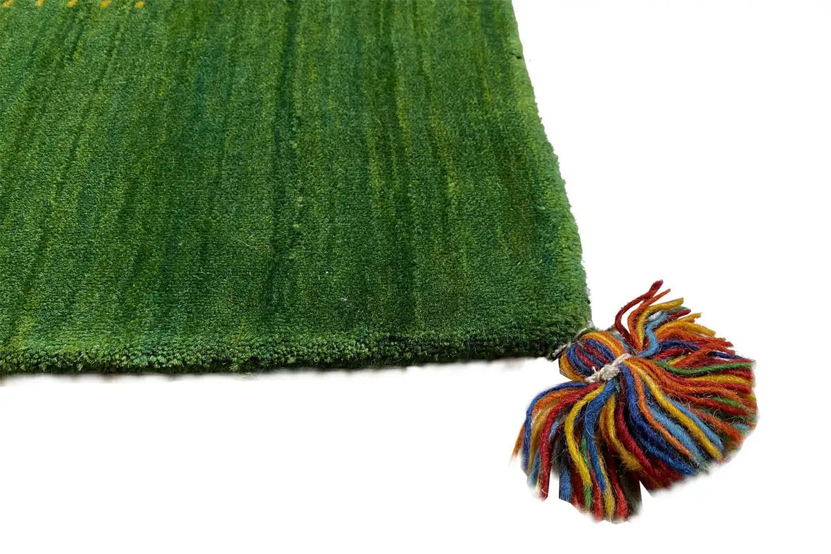 Green Gabbeh rug: close-up with colorful tassels and dense pile