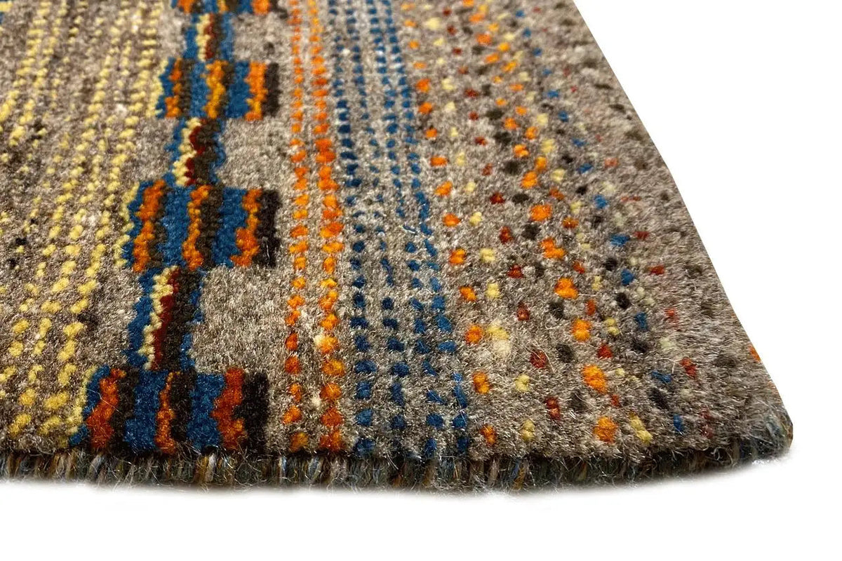 Gabbeh rug detail with fringes along the edge and colorful stripes in blue, yellow, and gray