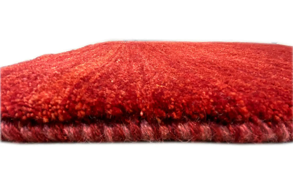 Gabbeh rug with red pile and visible rug edge, side view