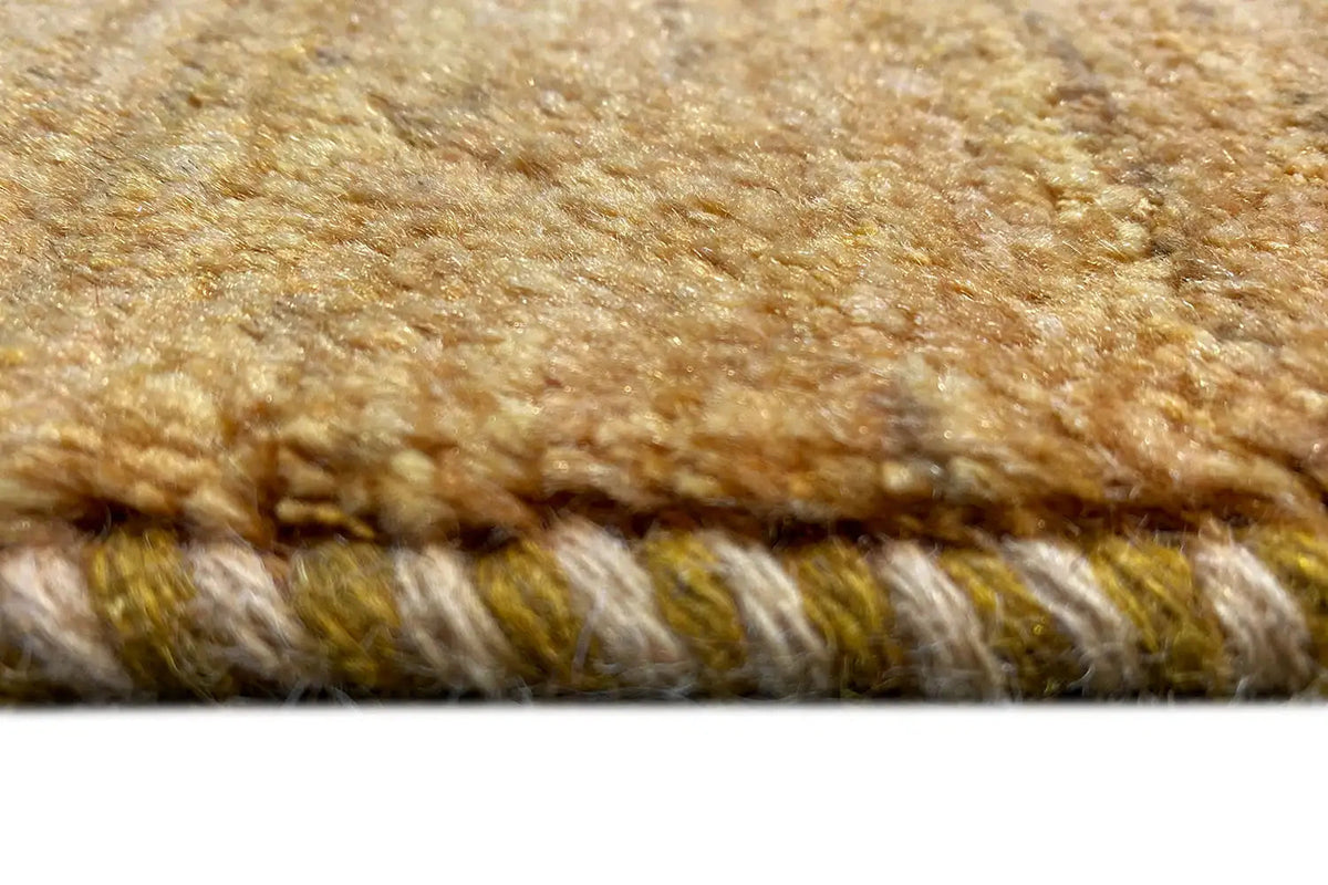 Golden-brown Gabbeh rug: detail of the shaggy fringes along the edge