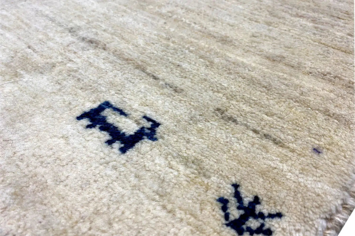 Gabbeh rug close-up: light beige with a blue pattern and pile texture