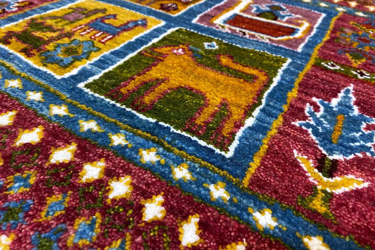 Gabbeh-Lori rug detail: colorful embroidered patterns on a reddish-brown pile with a blue border