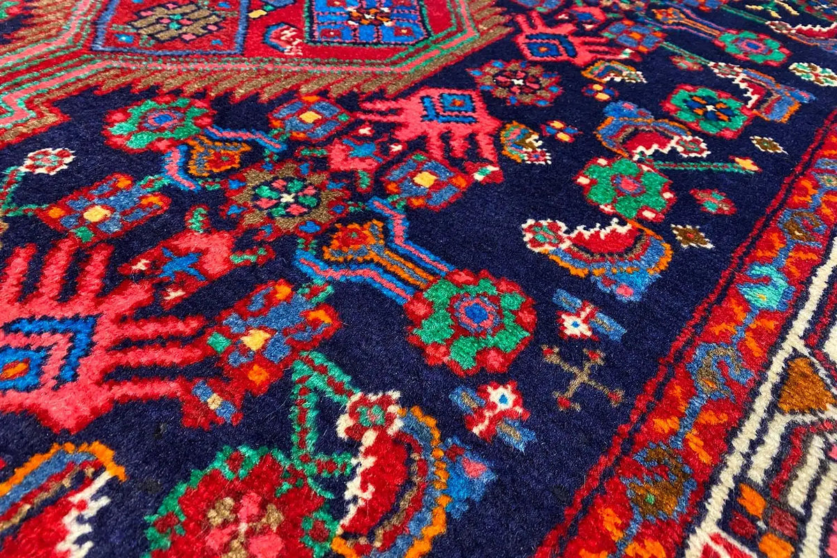 Close-up of runner rug: dark blue background with red, green, and turquoise patterns