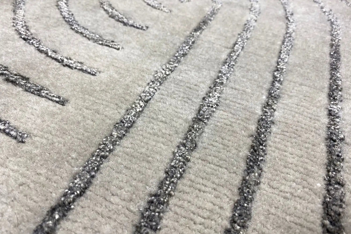 Close-up of a rug: gray pile with dark lines and mottled decorative edges