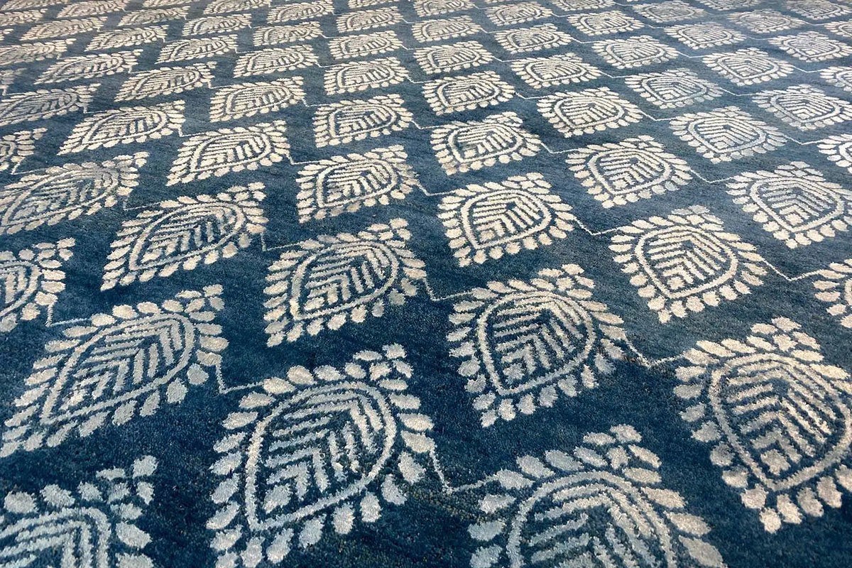 Designer rug close-up: blue ornamental pattern with cream-colored details, pile visible