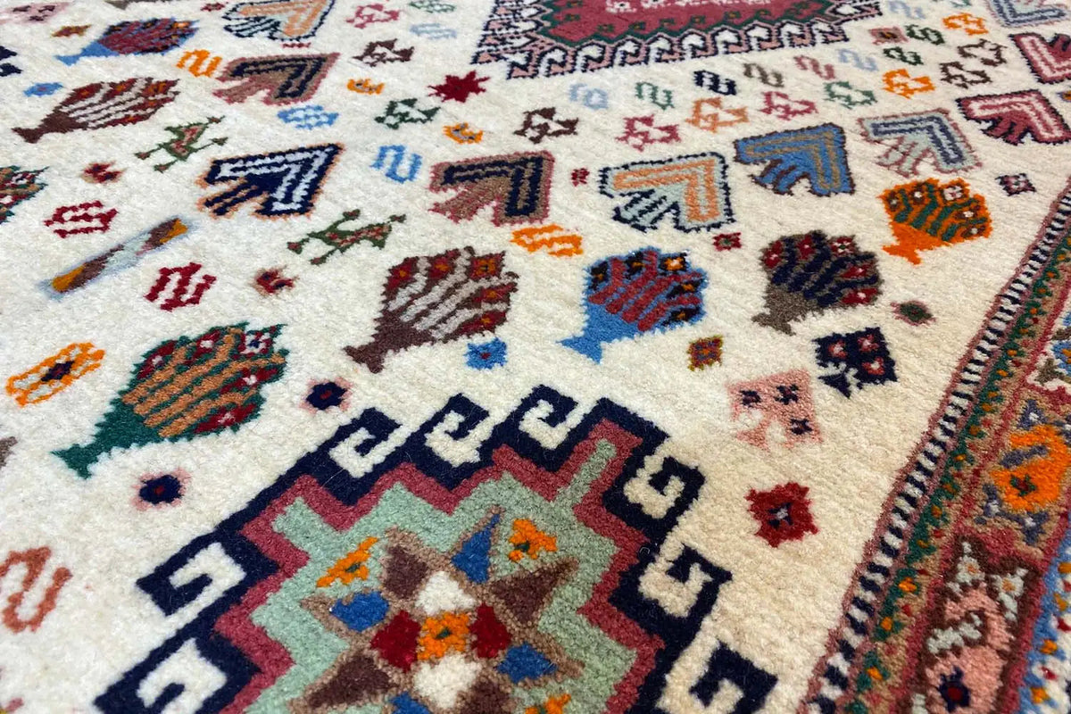 Oriental rug close-up: geometric motifs and border, cream-colored with blue/red