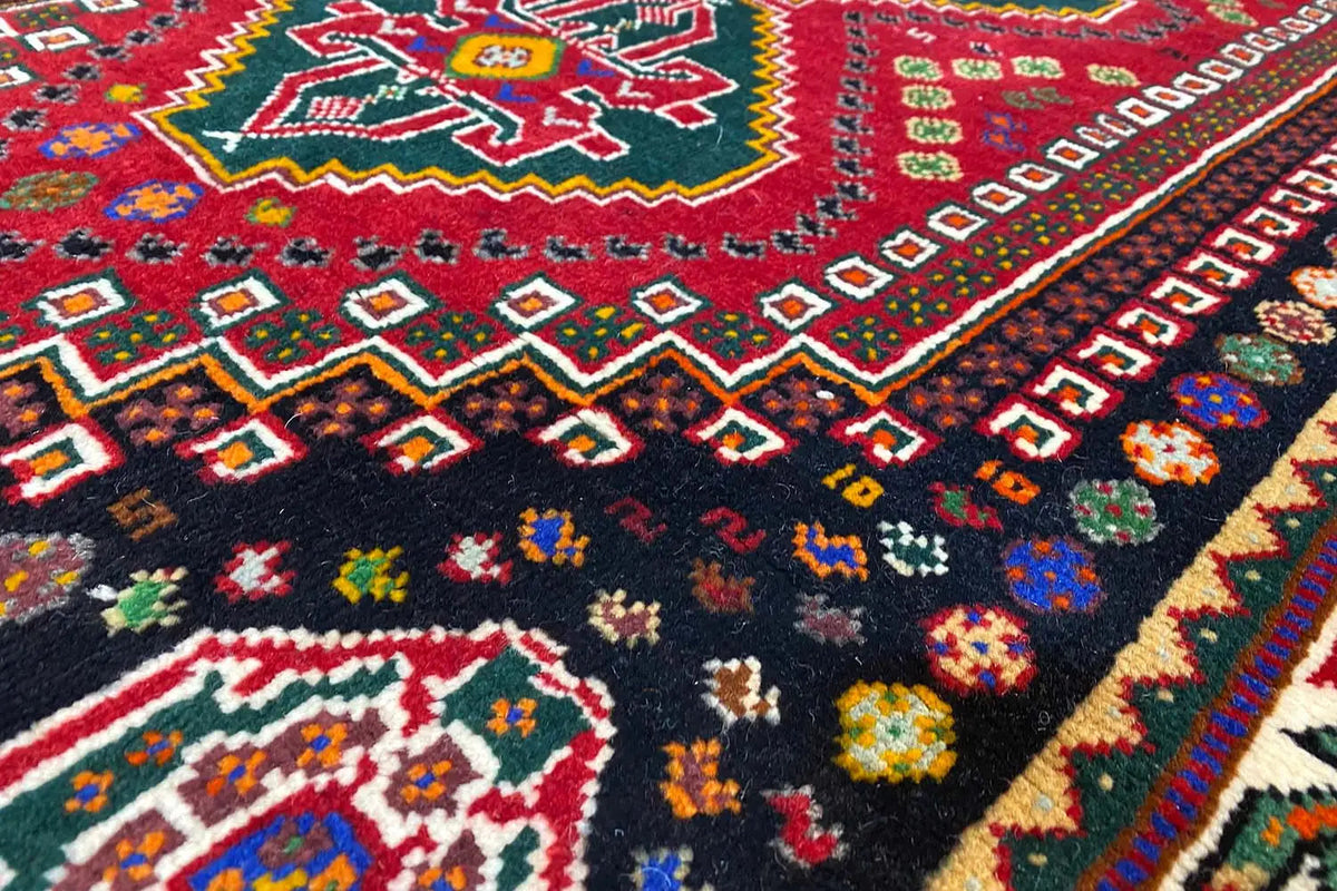 Close-up of a carpet surface with geometric patterns in red, blue, green, and colorful details