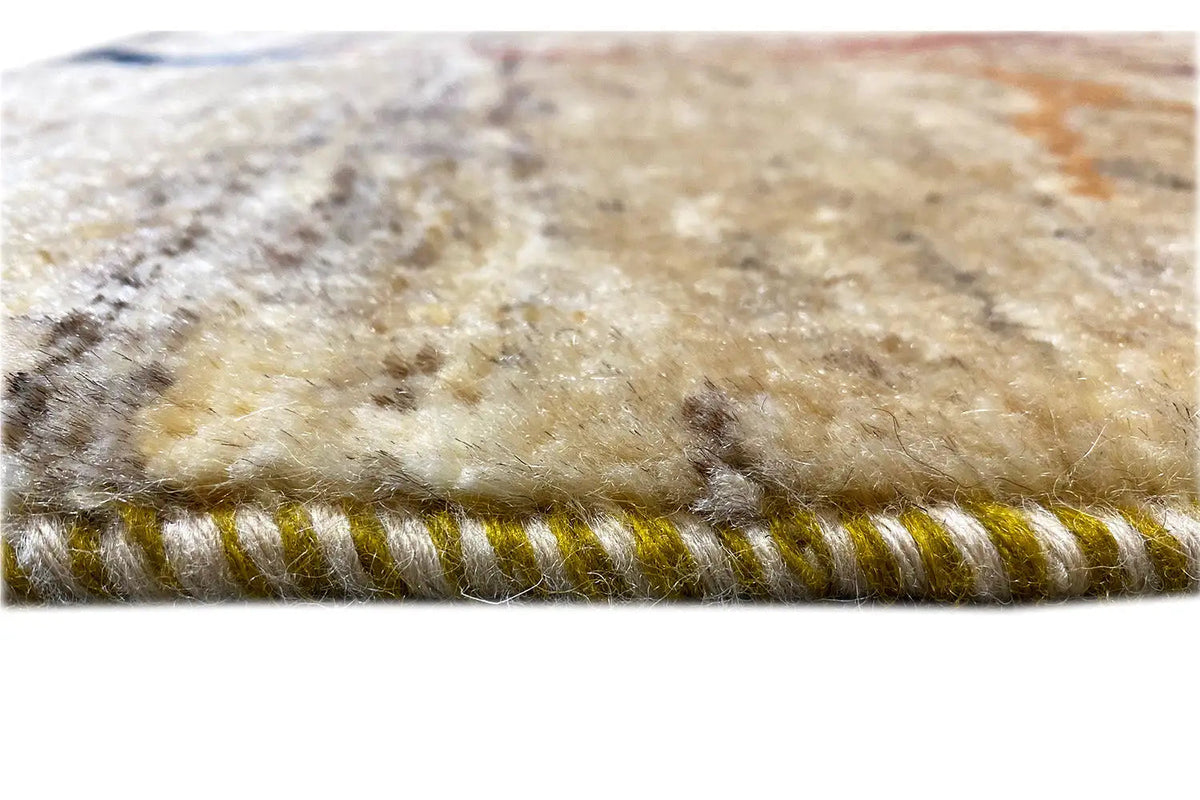 Close-up of a Gabbeh Lori rug (86x61 cm): beige pile with fringes along the edge.