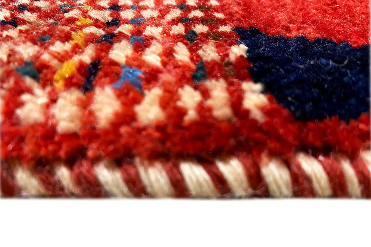 Close-up of carpet pile with a red background, multicolored border, and fringes