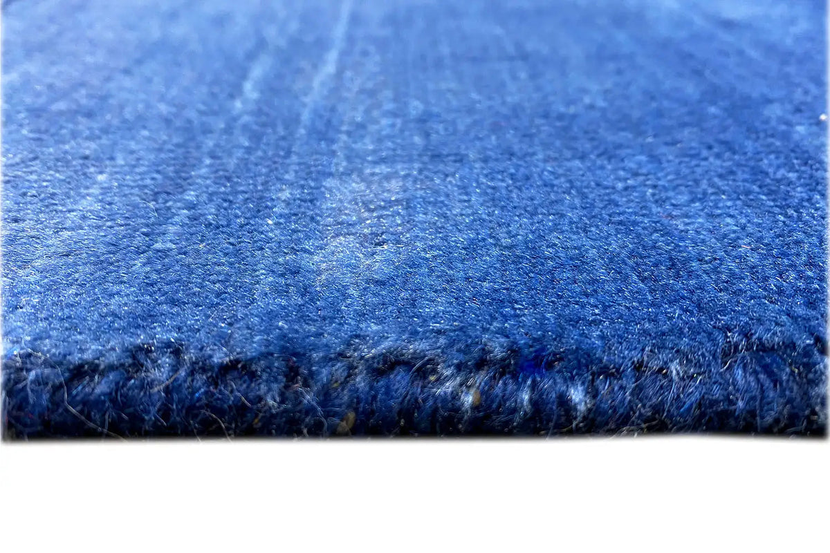 Close-up: blue rug with a dense pile and fringed edge