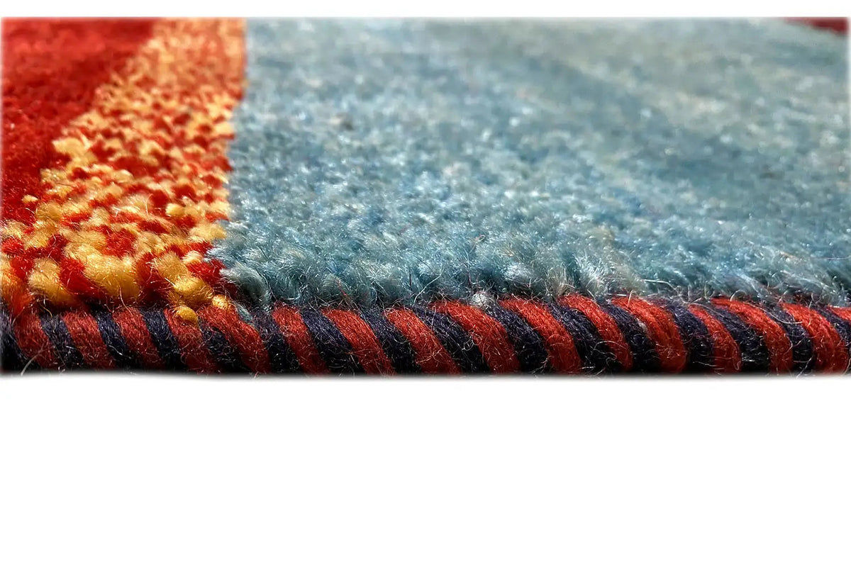 Gabbeh rug detail: fringed edge, blue with red and beige accents
