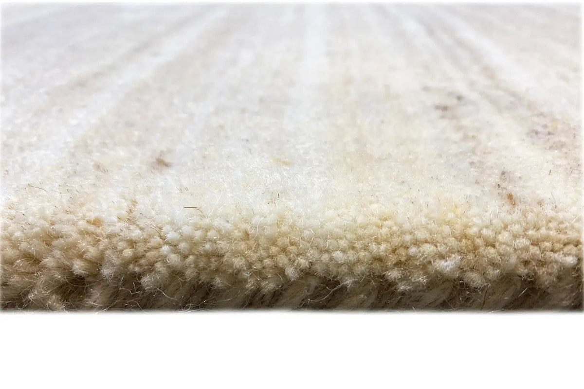 Rug edge: beige Gabbeh loom rug with a dense, short pile