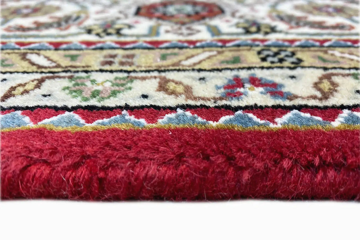 Carpet edge with a red pile and beige ornaments; close-up of the border.